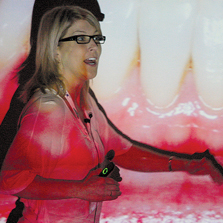 woman lecturing in front of an image of teeth and gums